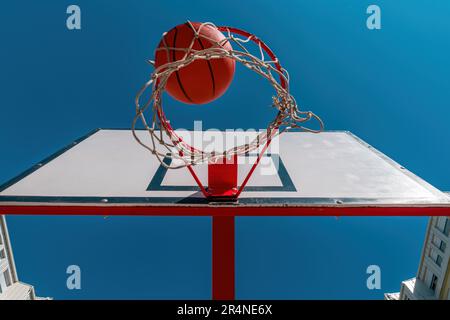 Vue en contre-angle du ballon tombant dans les paniers sur le terrain de basket-ball extérieur, mise au point sélective Banque D'Images