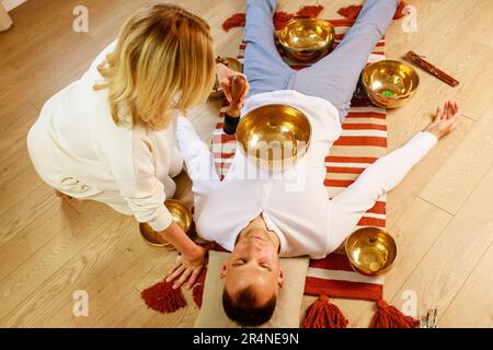 Femme jouant sur un bol de chant tibétien massage maling méditation pour un homme Banque D'Images