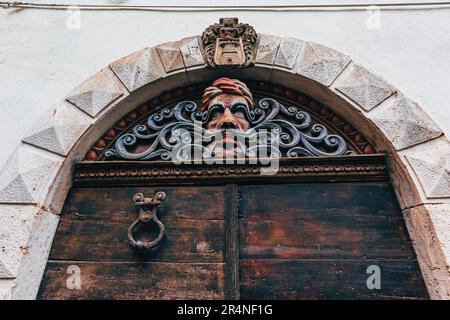 Porte en bois usée avec arcade dans la vieille ville de Lovran en bord de mer croate, vue à angle bas Banque D'Images