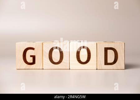 Le mot BON sur des cubes en bois sur un fond beige neutre studio. Copier l'espace. Écrit. Les mots de texte ont leur importance. Photo conceptuelle. Symbole d'approbation positive Banque D'Images