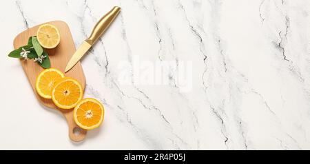 Planche à découper avec couteau, morceaux d'orange frais et de citron sur fond clair avec espace pour le texte Banque D'Images