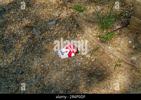 Le paquet de cigarettes Marlboro jeté a ouvert et a écrasé la boîte avec l'emballage en plastique à côté de poser sur le sol polluant l'environnement Banque D'Images