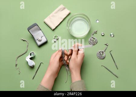 Femme nettoyant de beaux bijoux sur fond vert Banque D'Images