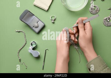 Femme nettoyant de beaux bijoux sur fond vert, gros plan Banque D'Images