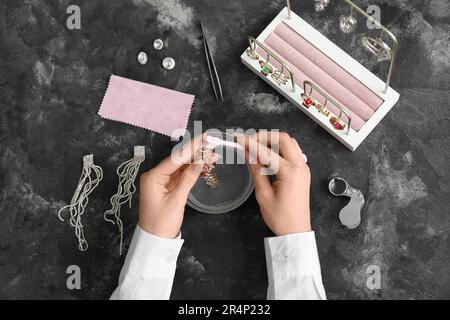 Femme nettoyant de beaux bijoux sur fond de grunge Banque D'Images