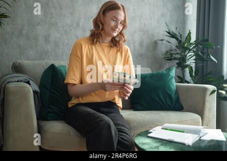 La jeune femme magnifique qui détient 20 billets en euros remplit ses factures travaille avec des papiers financiers à la maison compte sur la calculatrice avant de payer les recettes fiscales Banque D'Images