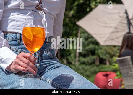 Une fille boit de l'alcool glacé cocktail Aperol spritz sur la terrasse d'été, dans un café ou un restaurant Banque D'Images