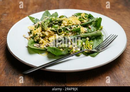 Assiette avec une salade de légumes maison au printemps avec asperges vertes, haricots fava et jeunes épinards. Banque D'Images