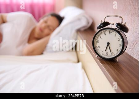 Concentrez-vous sur le réveil noir sur flou femme enceinte, femme enceinte en expectative dormant, napping le jour. Grossesse. Détente à la maison Banque D'Images