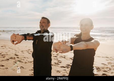 Souriant homme et femme européens matures faisant des exercices de bras, d'étirement et d'échauffement Banque D'Images