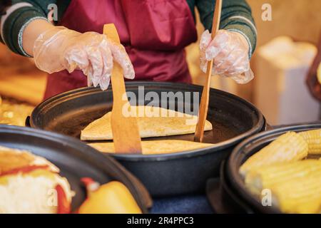 Mains de cuisinier en gants et en gros plan sur le tablier. Processus de préparation de quesadilla, burrito, fajitas. Extérieur vendant, cuisine authentique de la rue. Concept Banque D'Images