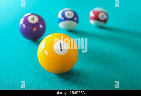 Un billard jaune numéro 1 sur une surface de table de billard verte avec un fond flou de boules colorées. Sports et loisirs en intérieur, compétition et winne Banque D'Images