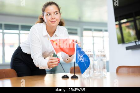 Femme d'affaires qui organise les drapeaux de l'OTAN (OTAN) et de la Chine pour présentation et négociations Banque D'Images