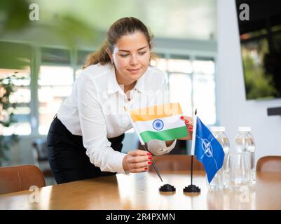 Femme d'affaires qui organise les drapeaux de l'OTAN (OTAN) et de l'Inde pour présentation et négociations Banque D'Images