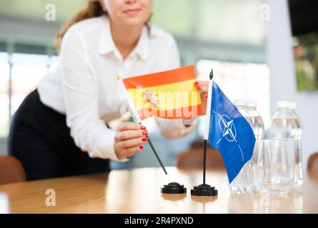 Femme d'affaires qui organise les drapeaux de l'OTAN (OTAN) et de l'Espagne pour la présentation et les négociations Banque D'Images