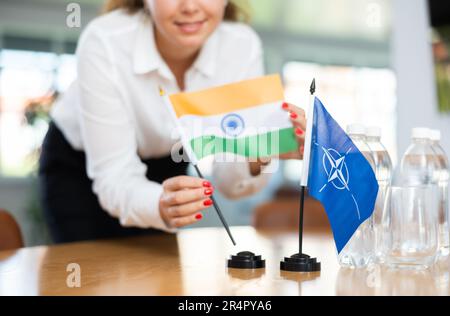 Femme d'affaires qui organise les drapeaux de l'OTAN (OTAN) et de l'Inde pour présentation et négociations Banque D'Images