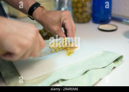 Homme mains coupant des olives. Couteau japonais. Cuisine Banque D'Images