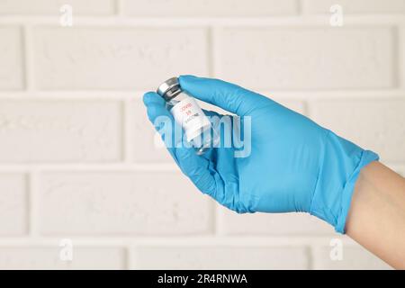 Médecin tenant le tube avec le vaccin du coronavirus pour le virus 2019-nCoV COVID sur fond blanc. Vue de dessus. Banque D'Images