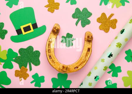 Trèfle vert et fer à cheval doré sur fond rose pour St. Fête de la Patrick. Vue de dessus. Banque D'Images