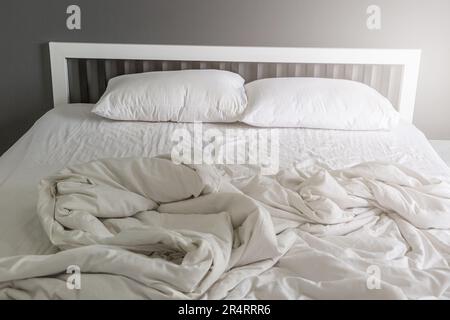 Deux oreillers blancs sur le lit avec une couverture en désordre dans le fond de la chambre Banque D'Images