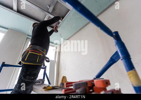Installation au plafond avec des techniciens experts dans la salle en cours de construction. Banque D'Images