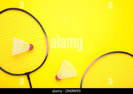 Shuttlecocks et raquettes de badminton sur fond jaune. Vue de dessus. Banque D'Images