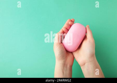 Femme main tenant une barre de savon rose sur un fond de menthe. Vue de dessus Banque D'Images