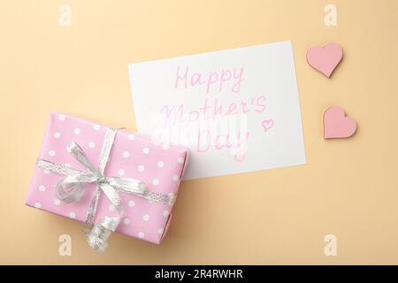 Carte de fête des mères sur fond beige avec cadeau. Bonne journée des mères. Vue de dessus Banque D'Images