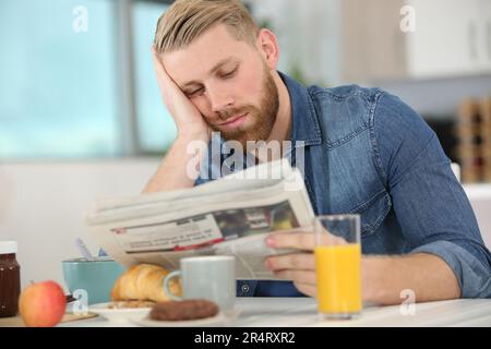 homme lisant le journal tout en prenant le petit déjeuner Banque D'Images