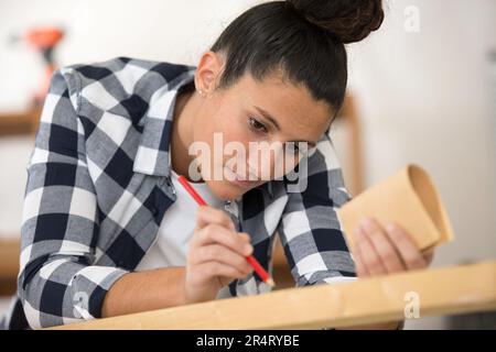 marquage de menuisier femelle sur planche en bois avec crayon Banque D'Images