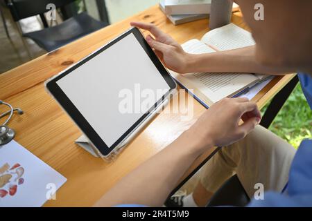 Gros plan de l'étudiant en médecine homme utilisant la tablette numérique, se préparant pour les examens universitaires dans la bibliothèque Banque D'Images