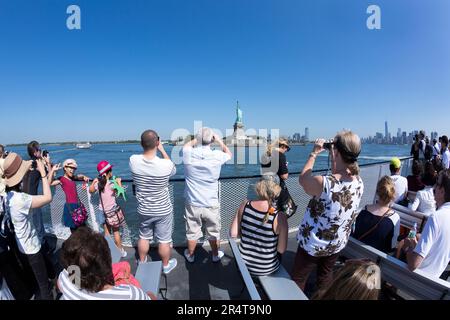 NOUS, New York, touristes prenant des photos de la statue de la liberté. Banque D'Images