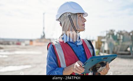 Femme d'âge moyen à cheveux gris constructeur utilisant le pavé tactile dans la rue Banque D'Images