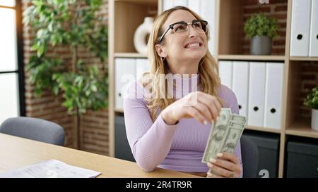 Jeune belle femme hispanique d'affaires femme tenant des dollars au bureau Banque D'Images
