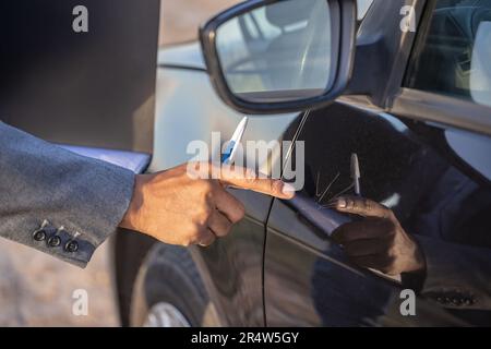 Détail d'une main d'un agent d'assurance montrant une rayure sur une voiture. Banque D'Images