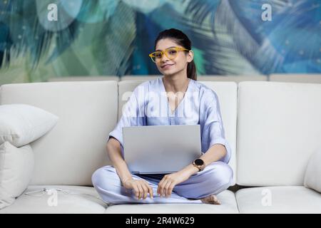 Photo pleine longueur de l'étudiant positif fille s'asseoir plancher jambes croisées travail plié travail distant ordinateur portable lire rapport de document Banque D'Images