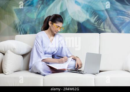 Photo pleine longueur de l'étudiant positif fille s'asseoir plancher jambes croisées travail plié travail distant ordinateur portable lire rapport de document Banque D'Images