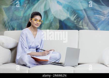 Photo pleine longueur de l'étudiant positif fille s'asseoir plancher jambes croisées travail plié travail distant ordinateur portable lire rapport de document Banque D'Images