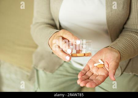 Femme âgée malade tenant des pilules sur sa main puant des capsules de la bouteille. Banque D'Images