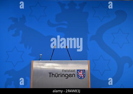 30 mai 2023, Thuringe, Erfurt: Le pupitre avec microphones et l'inscription 'Free State of Thuringe' comprenant des armoiries devant un mur bleu avec les armoiries de Thuringe lors de la conférence de presse du gouvernement. Photo: Martin Schutt/dpa Banque D'Images