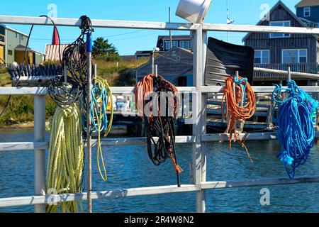 Corde de pêche industrielle tressée pour utilisation intensive enroulée. Une grande corde épaisse de style usé et tissé est empilée à côté d'une petite corde de pêche de câble vert effilochée. Banque D'Images