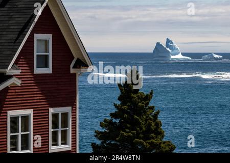 Une maison de style cottage de deux étages aux couleurs rouges vives avec fenêtres en verre donnant sur l'océan bleu. Au loin, il y a une grande glace blanche sur glacier Banque D'Images