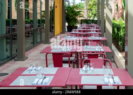 La terrasse extérieure d'une petite entrée de restaurant avec chaises rétro vides, bancs et tables en bois. Le bâtiment dispose de fenêtres en verre et d'une porte. Banque D'Images