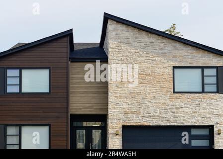 Vue sur la rue d'une maison moderne de style suburbain. Il y a un patio, les murs extérieurs sont parements bruns, et le rocher beige, et la porte de garage est une grande marron Banque D'Images