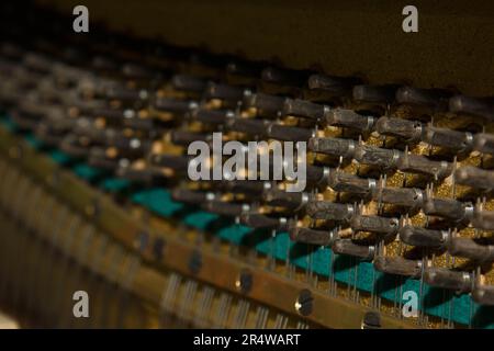 Réparation d'un instrument de musique à cordes. L'intérieur d'un piano avec cordes en laiton et un maillet en bois. Instrument de musique à l'ancienne pour pe Banque D'Images