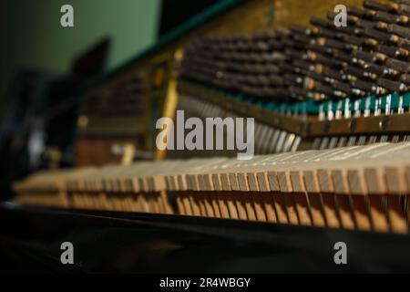 Réparation d'un instrument de musique à cordes. Vue intérieure d'un piano à cordes en laiton et d'un maillet en bois. Un instrument de musique pour le spectacle de musi Banque D'Images