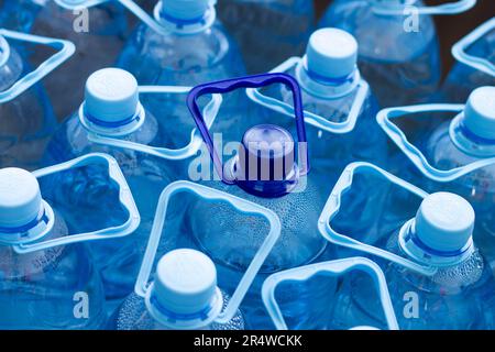 De nombreuses bouteilles en plastique bleu avec bouchons bleus et une avec bouchon bleu foncé avec eau minérale claire dans un supermarché. Eau pure, filtrée et écologique Banque D'Images