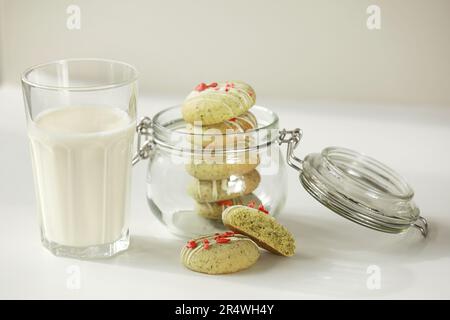 Composition avec biscuits maison au pain d'épice à la menthe avec matcha et fraises sublimées dans une assiette, verre de lait, pot et fleurs sauvages dans un vase sur la ba Banque D'Images