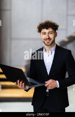 Portrait of handsome businessman smiling while using laptop in office Banque D'Images