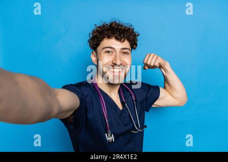 Autoportrait d'homme gai attrayant avec le selfie de tir de chaume avec deux mains sur l'appareil photo avant ayant stérile, protecteur, masque facial, portant la Banque D'Images